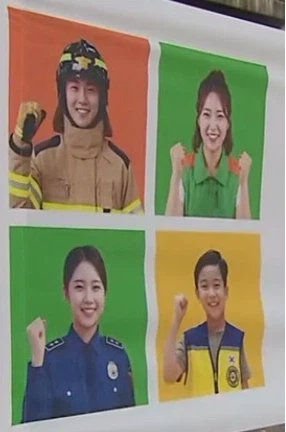 안전훈련 현수막에 표현된 소방관과 경찰 등 네 인물